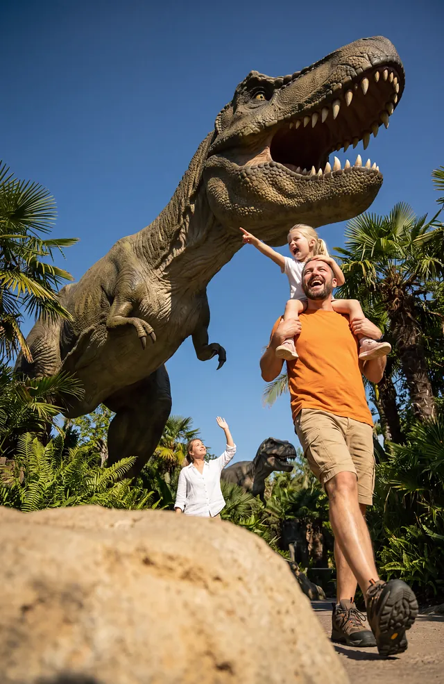 A father and child beside a life-size dinosaur